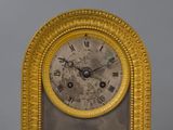 a gold clock with roman numerals on the face