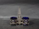 a silver and blue glass holder with a tower in the background