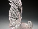 une sculpture en verre transparent représentant un oiseau posé sur une surface noire