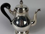an antique silver teapot with a black handle on a white surface