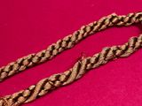 a close up of a gold chain on a pink surface