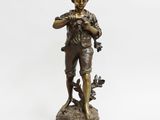 une statue en bronze représentant un garçon avec un oiseau sur l'épaule