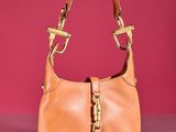 tan leather purse with gold hardware on a shiny surface