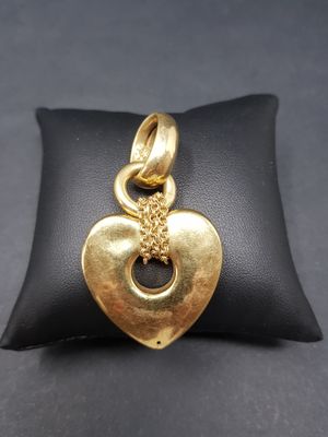 a gold heart charm sitting on top of a black pillow