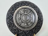 an ornate silver plate with a bird on it on a stand