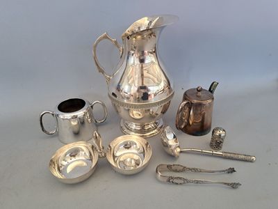 a silver pitcher and other silverware on a table