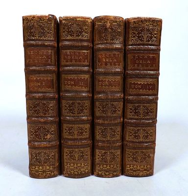 six old books are lined up in a row on a white surface