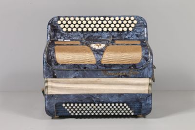 an old blue accordion sitting on top of a white table