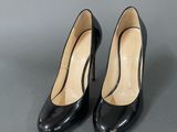 a pair of black high heeled shoes on a grey surface
