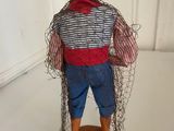 a small doll with a red hat and blue pants and a red hat