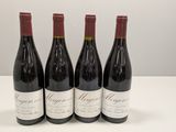 quatre bouteilles de vin rouge sont posées sur une table blanche