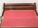 a small wooden desk with a red mat on it