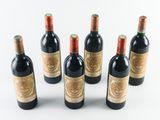 six bottles of red wine lined up in a row on a white surface