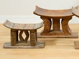 un banc en bois et deux petits tabourets posés sur un parquet