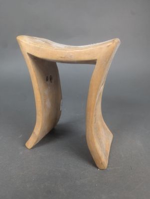 une image représentant un petit tabouret en bois posé sur une surface grise