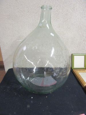 a large glass vase sitting on a table next to a picture frame