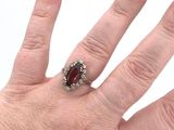 woman ' s hand with red manicured nails and a ring with a red stone