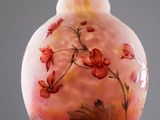 a glass vase with flowers painted on it sitting on a table