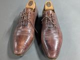 pair of brown leather shoes with laces on top of a gray surface