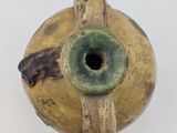a small vase with a hole in it on a white surface