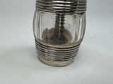 a glass jar with a silver lid on a white surface
