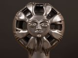a silver sculpture of a sun face on a black background