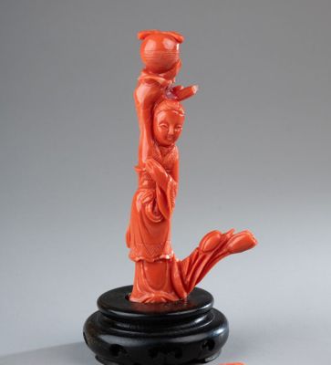 une sculpture orange représentant une femme tenant un pot, posée sur un socle noir