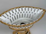 a white and gold bowl on a stand on a white surface