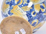 a blue and yellow vase sitting on a white surface