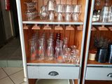 bottles and glasses on a shelf in a kitchen with tile flooring
