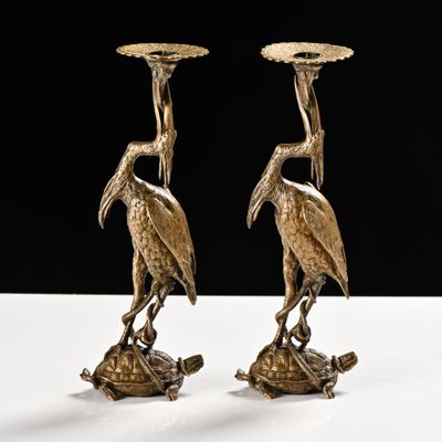 une paire de bougeoirs anciens en laiton ornés d'oiseaux sur le dessus