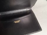 someone is holding a black wallet with a gold logo on it