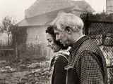 photo en noir et blanc d'un homme et d'une femme debout devant une clôture