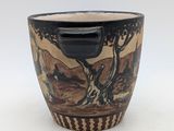 a black and brown cup with a painting on it