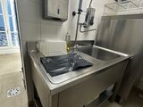 évier en acier inoxydable dans une cuisine professionnelle, avec une fenêtre en arrière-plan