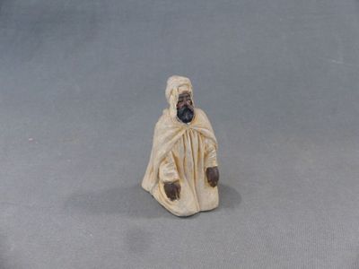 figurine représentant un homme vêtu d'une robe blanche et portant une barbe noire