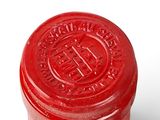 red waxed jar with lid on a white background
