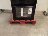 a black oven sitting on a pallet in a room
