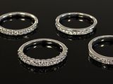six silver rings with diamonds on a black surface