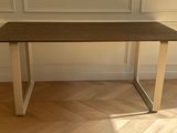 une table en bois avec un piètement en métal posée sur un parquet en bois dur