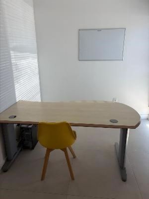 a desk with a yellow chair and a white board on the wall