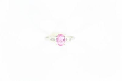 une bague sertie d'un saphir rose et de diamants sur fond blanc