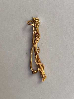 une image représentant une broche plaquée or sur laquelle figure une femme tenant une épée
