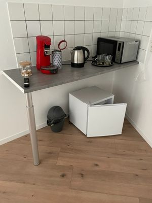 une petite cuisine avec un micro-ondes, un grille-pain, un grille-pain et une cafetière posés sur le plan de travail