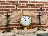 a clock sitting on top of a mantle next to two candles