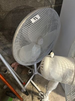 un ventilateur posé par terre à côté d'une chaise