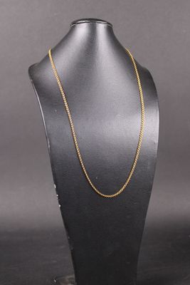 a gold chain necklace on a black mannequin stand