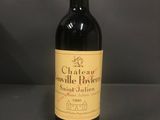 une bouteille de vin rouge posée sur une table, sur fond gris