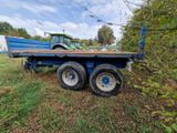 a blue flatbed trailer with a tractor in the background