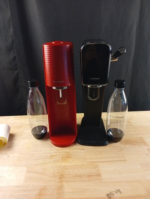 une cafetière rouge posée sur une table, à côté d'une bouteille d'eau